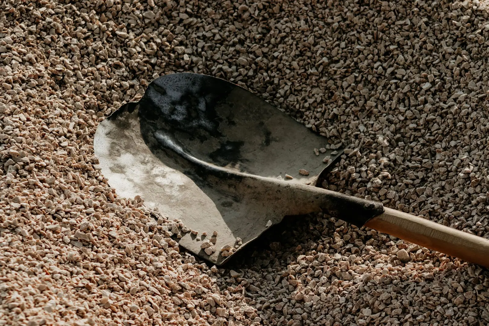 A metal scoop resting in a litter box of granular litter