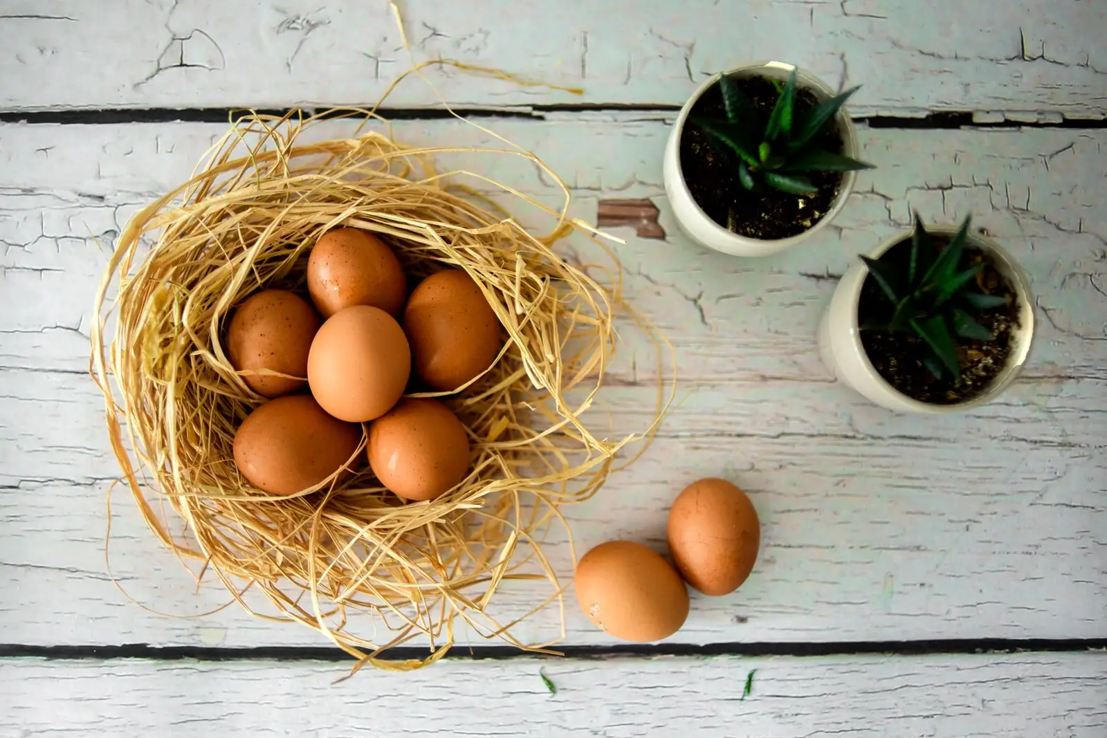Brown eggs in a straw nest on a weathered wooden table